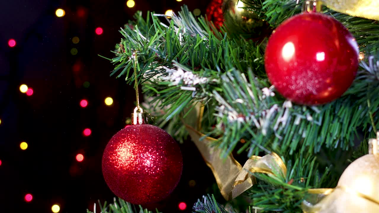 poniendo un ornamento de brillo rojo en el árbol de navidad con luces parpadeantes detrás