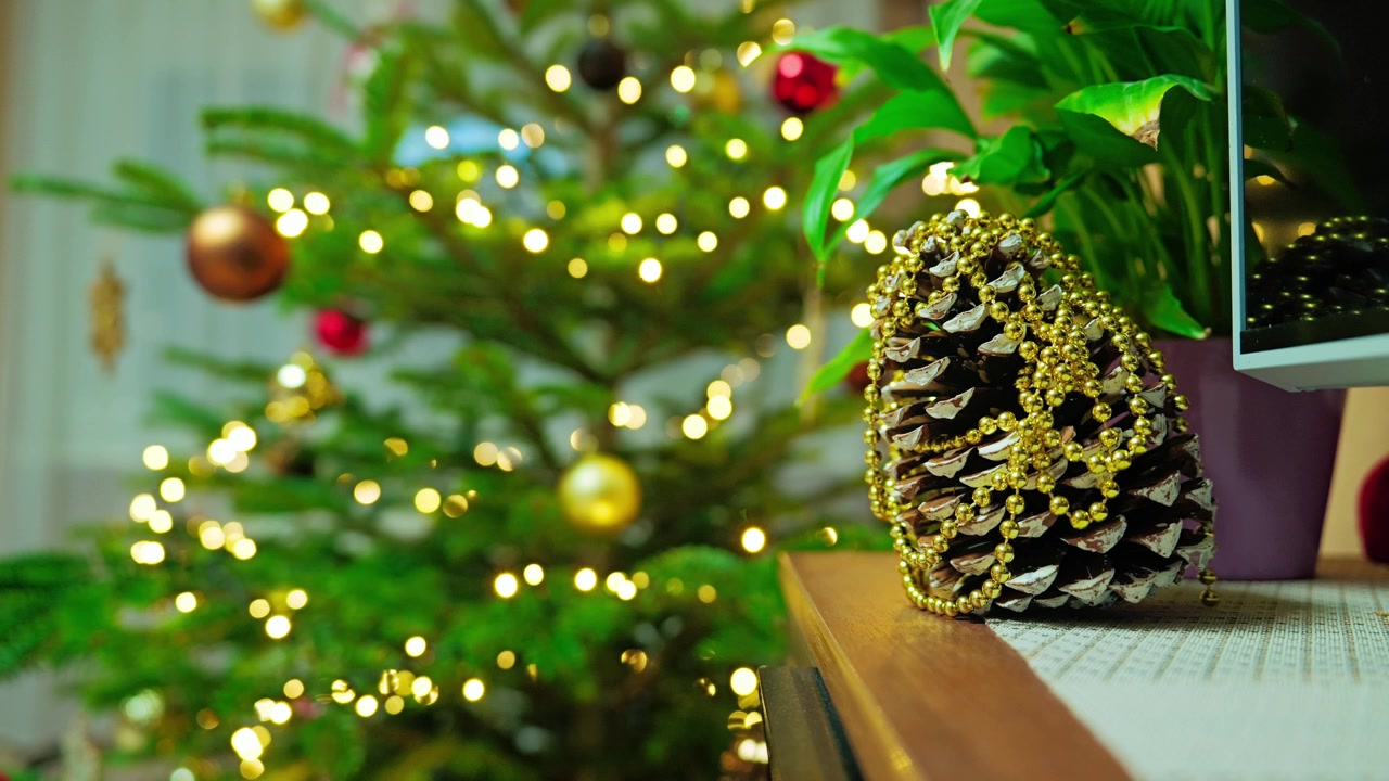 Pinha decorativa ao lado da árvore de Natal, com luzes festivas a brilhar ao fundo
