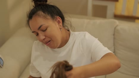 pregnant mother styling her daughter's hair at home