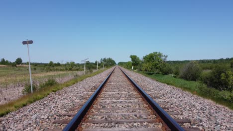 point of view from the front of a train travelling down the train tracks in the summertime