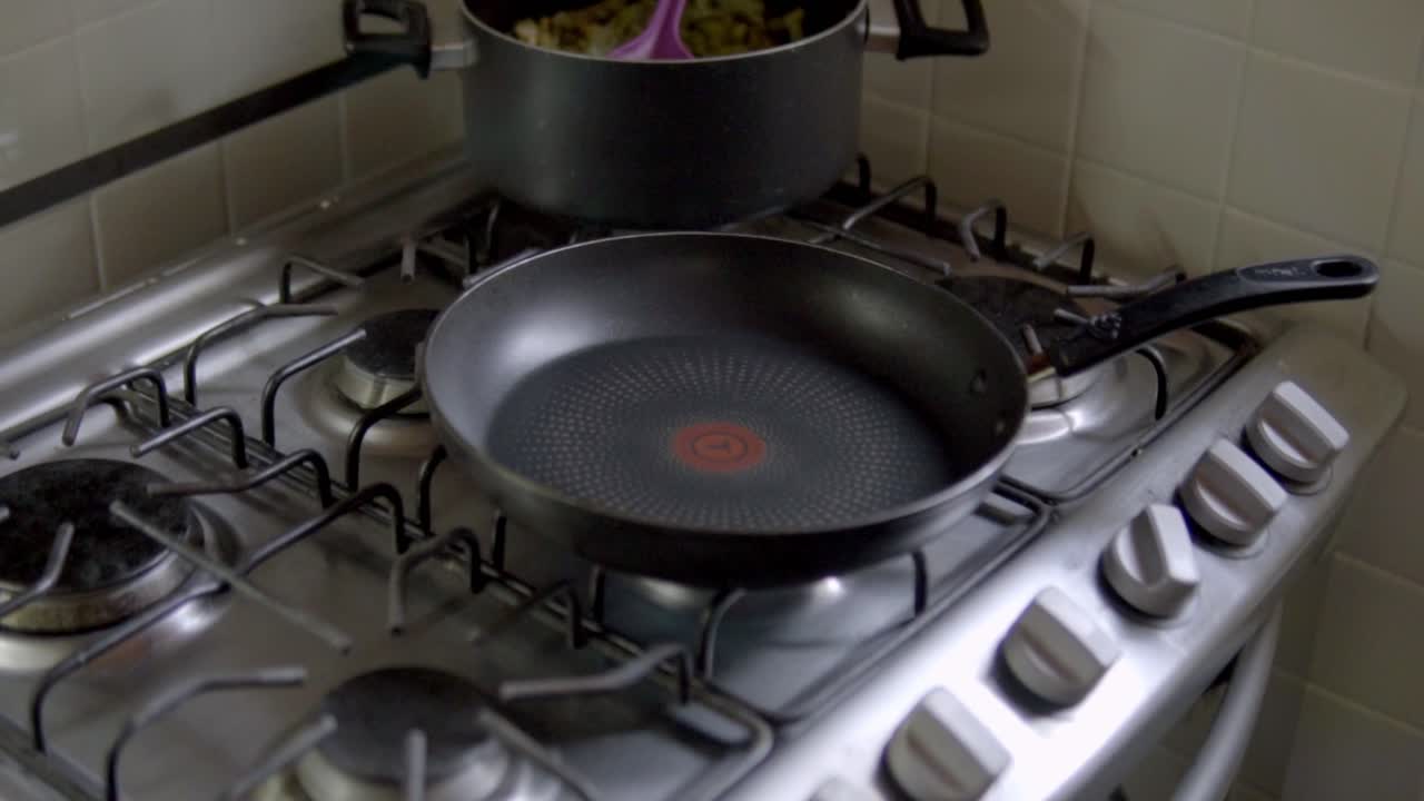 Primo piano di una padella vuota posizionata su un fornello a gas, che mostra la fase di preparazione del calore della superficie pulita e l'allestimento della cucina prima del processo di cottura a casa.