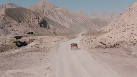 Roadtrip-on-dusty-canyon-road-in-Qinghai-Province,-China,-aerial-follow-shot