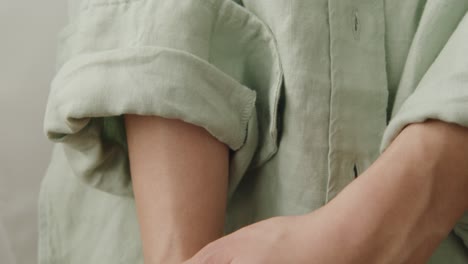 mujer sostiene el brazo con camisa verde enrollada