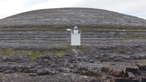 a lone white lighthouse stands tall against the rugged karst landscape of the burren
