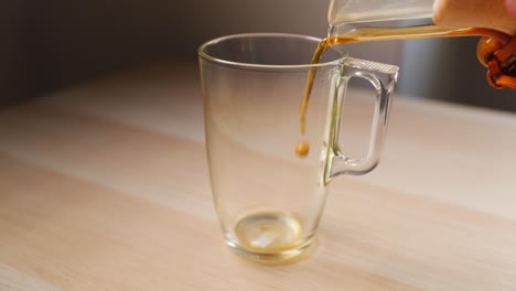 Eingießen-Von-Kaffee-Aus-Einer-Glas-French-Press-Mit-Holzgriff,-Von-Unten-Betrachtet-Auf-Ein-Hohes-Glas,-Eingefangen-Durch-Eingießen-Von-Kaffee-Und-Blasen-An-Der-Seite,-In-Zeitlupe-Mit-120-Bildern-Pro-Sekunde-Aufgenommen