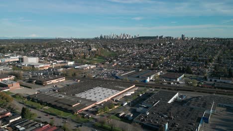 drone shot going backward over burnaby district in east vancouver, vancouver suburban area with burnaby skyscraper in the background on a sunny day, british columbia, canada