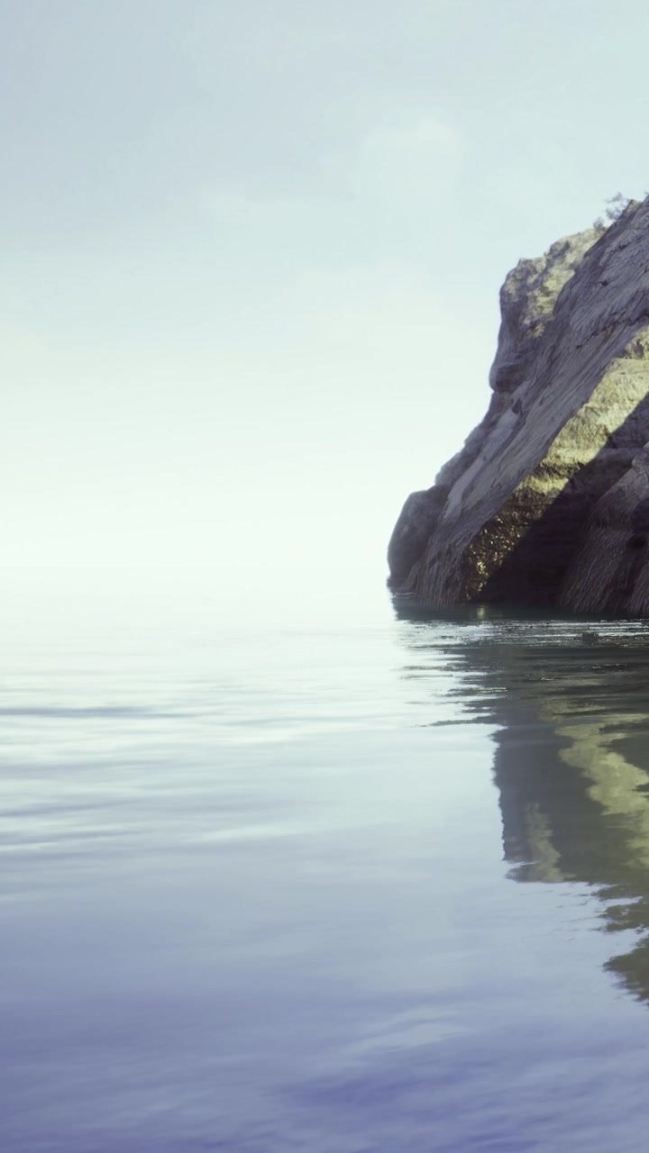 Serene waters reflect the gentle cliff at sunrise in a peaceful setting