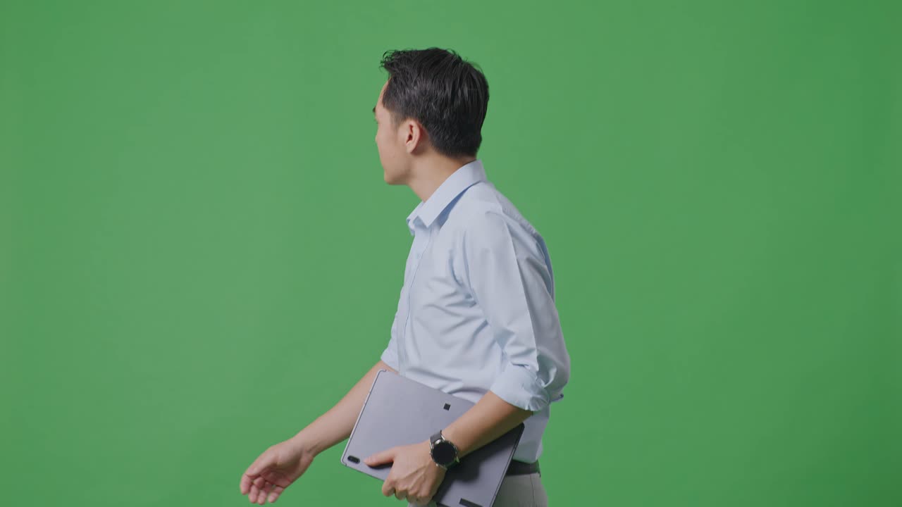 태블릿을 들고 스튜디오에서 녹색 화면 배경에서 고 있는 아시아 사업가의 측면 시각