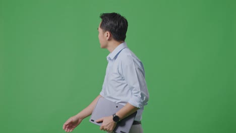 태블릿을 들고 스튜디오에서 녹색 화면 배경에서 고 있는 아시아 사업가의 측면 시각