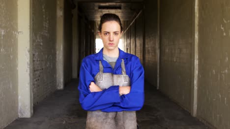 Female-welder-standing-with-arm-crossed-in-workshop