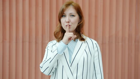 woman shushing, wearing striped blazer