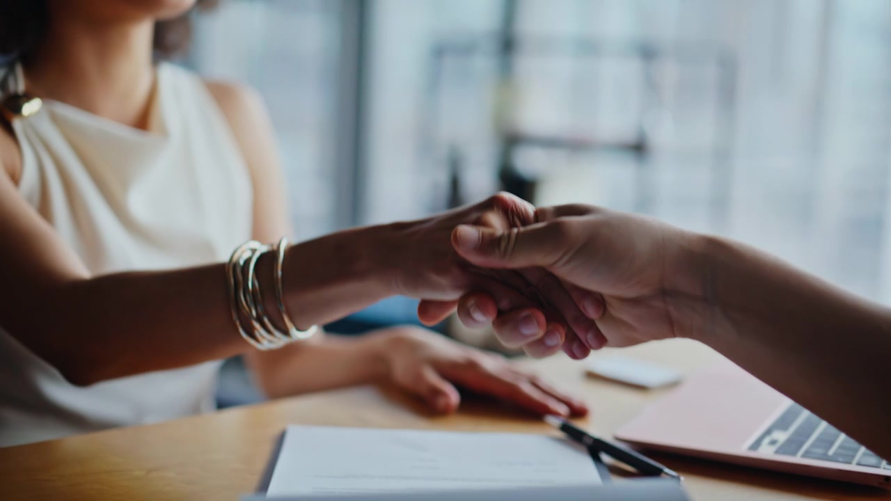Gros plan sur des mains signant un contrat commercial. Des femmes se serrent la main pour un accord au bureau.