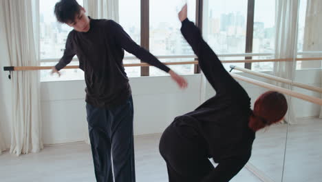 young couple practicing contemporary dance in front of mirror at studio