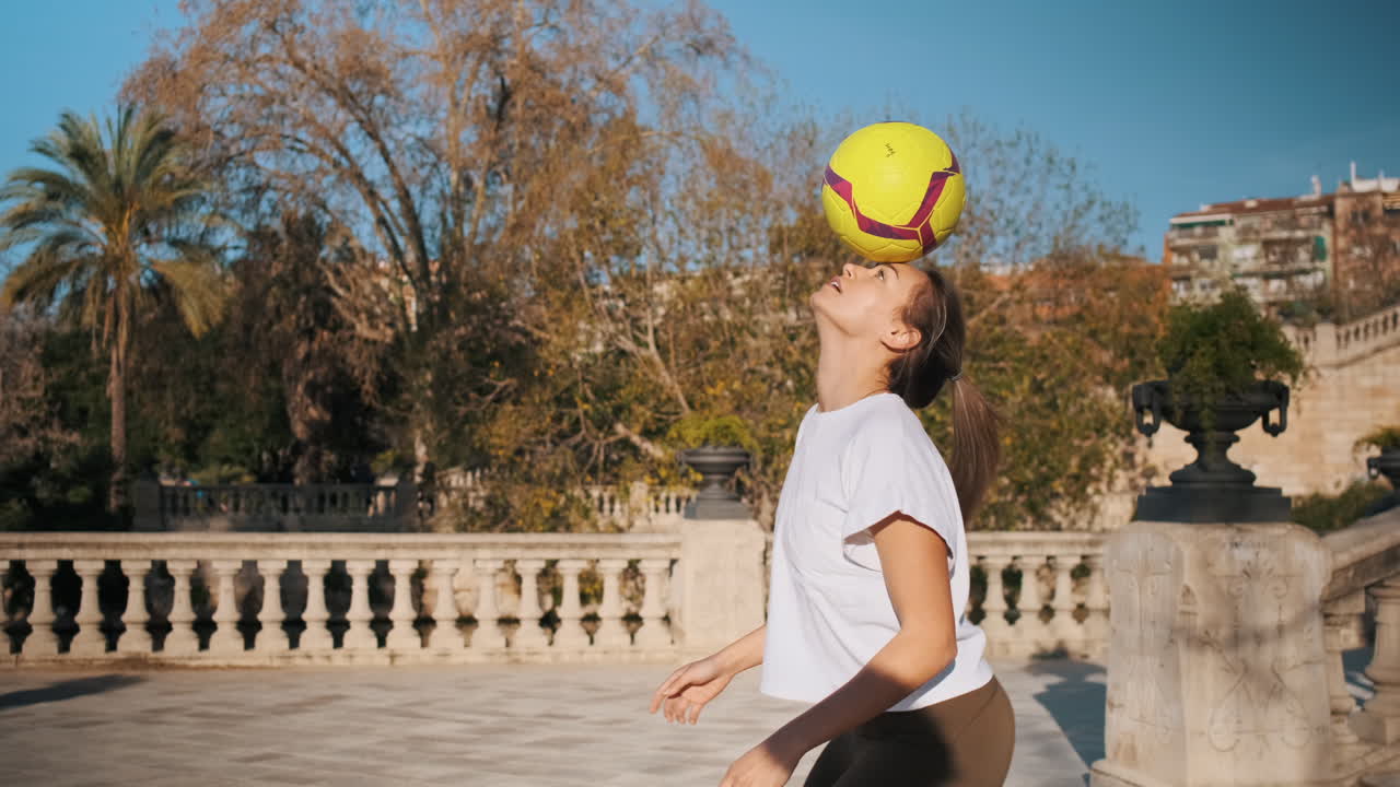 una mujer caucásica haciendo trucos de fútbol en la ciudad.