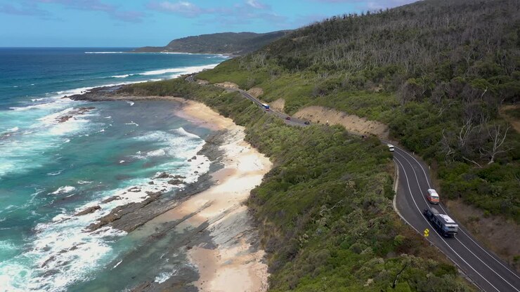 Vista aerea della Great Ocean Road con autobus, furgone, roulotte e auto, Victoria, Australia