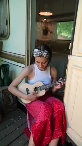 teenage girl playing ukulele in campervan