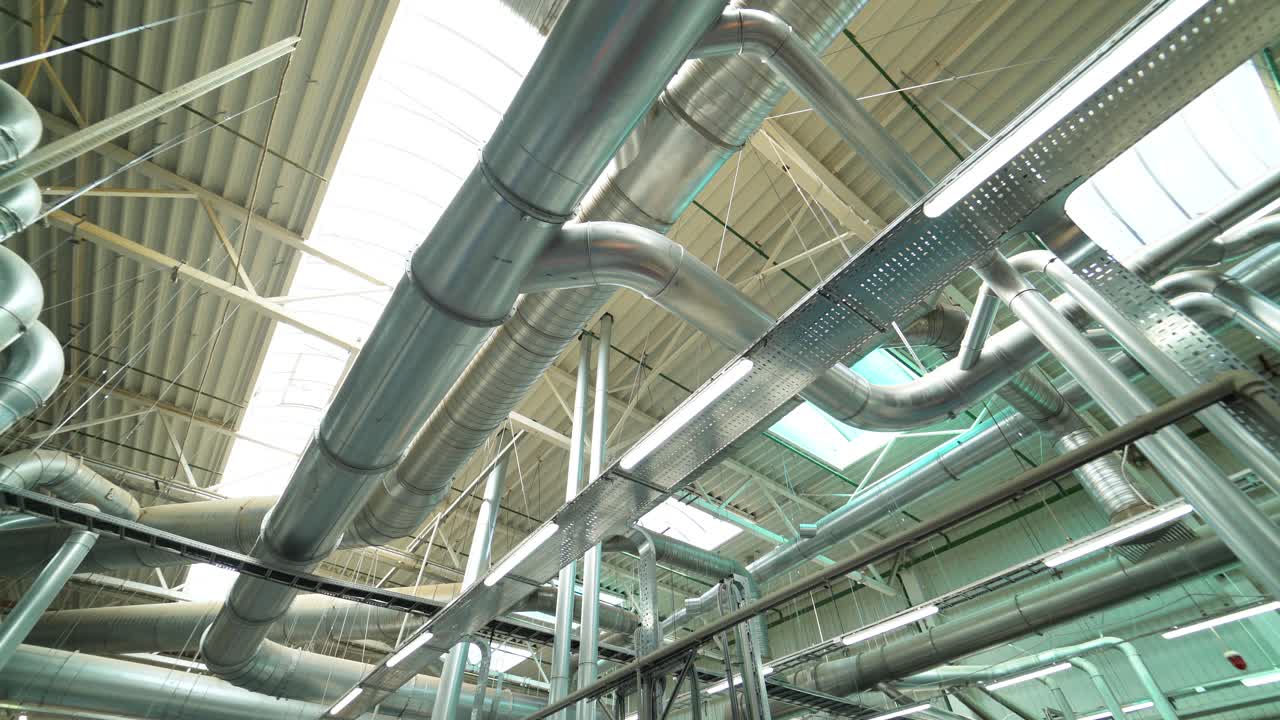 Pipes of the ventilation system are located on the ceiling of plant with the production of parquet. Camera motion to left