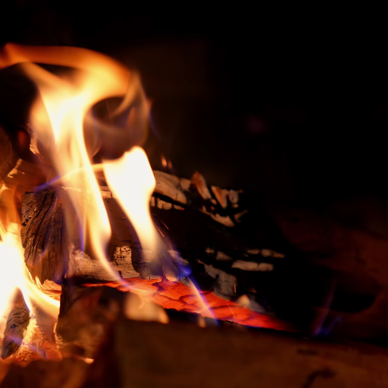 Bright fire on dark background. Wooden logs burning in beautiful vivid fire in fireplace. Warm cozy fire in a fireplace. Close-up