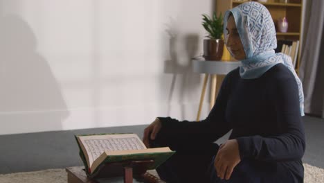 muslim woman at home sitting and reciting from the quran