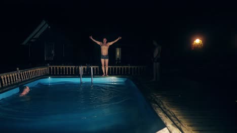 young guys dive into the pool at night