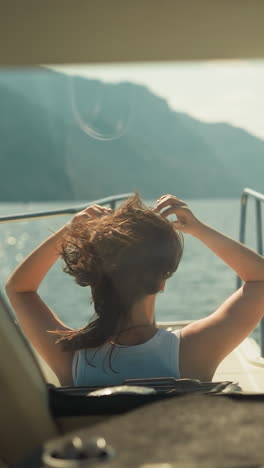 woman enjoys vacation by sailing along river taking in serene beauty of exotic resort nestled amidst mountains. relax and watch nature from cabin hatch