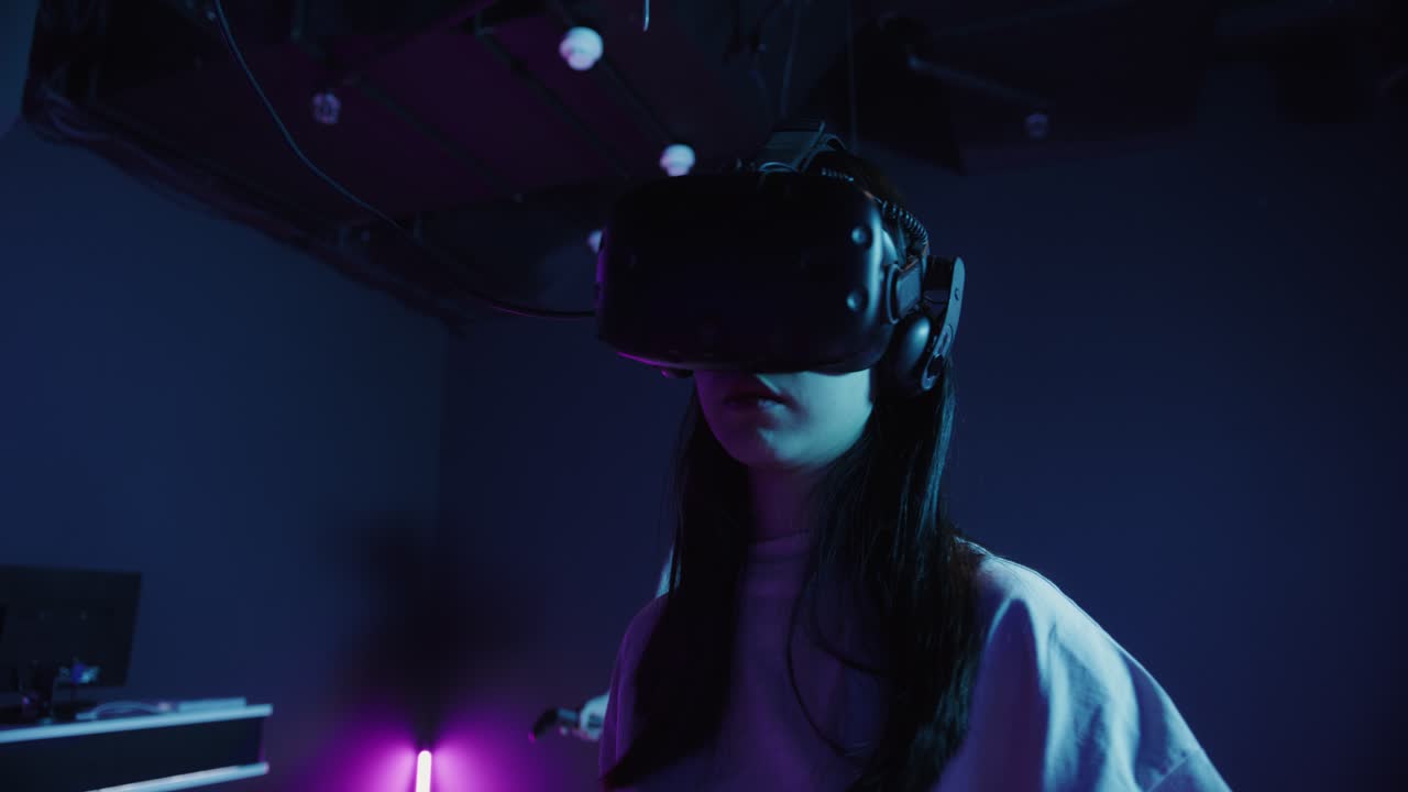 donna che indossa cuffie vr e controller in una sala giochi vr
