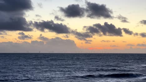 parque eólico marino de gran angular en medio del océano al atardecer