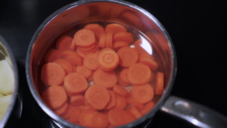 Carrots-and-potatoes-in-saucepans-on-hob-orange-and-white-movement