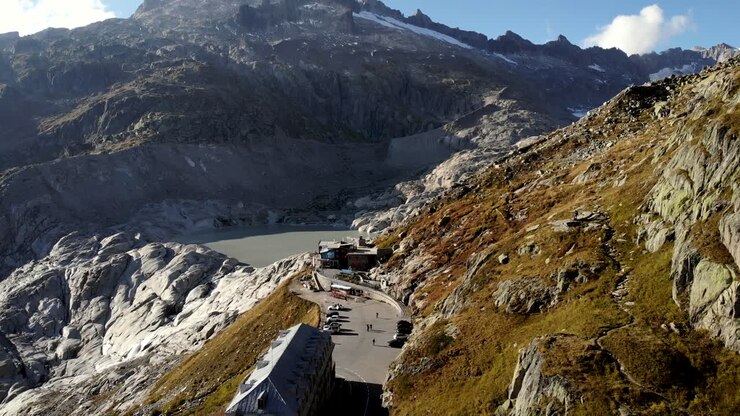 Aerial flyover over Furka mountain pass at the border of Valais and Uri in Switzerland with a view of the road leading to the closed hotel next to the Rhone glacier