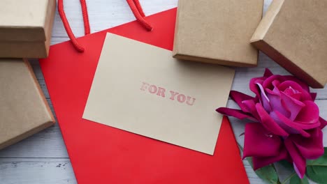 top view of gift box and rose flower on red background