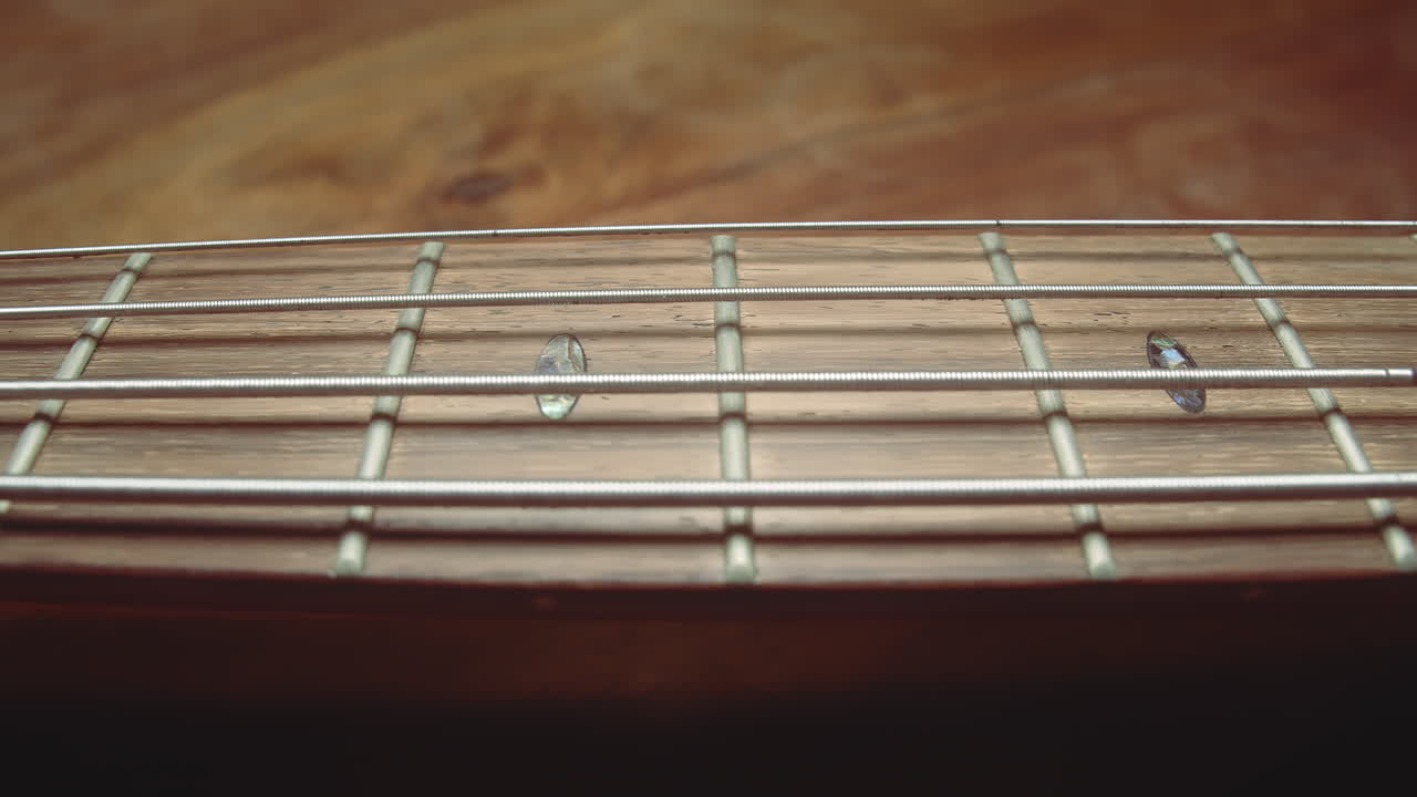 Gentle slider along bass guitar strings following neck
