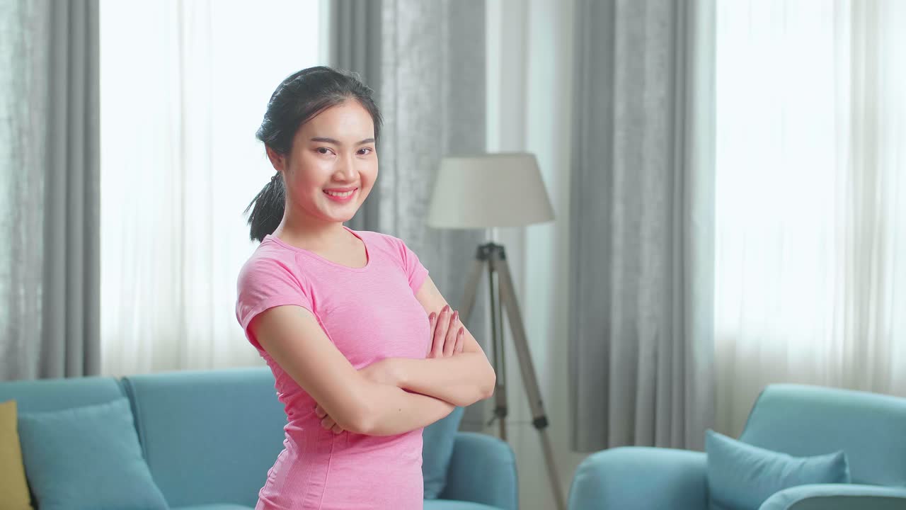 Asian Girl In Sportswear Is Posing With A Soft Smile In Her Living Room