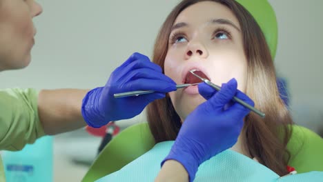 cerca de las manos del dentista examinando los dientes del paciente con el espejo de la boca