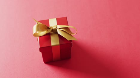 Video-of-red-christmas-gift-and-copy-space-on-red-background