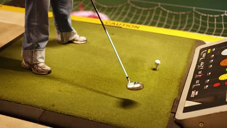 woman practicing golf swing at indoor driving range