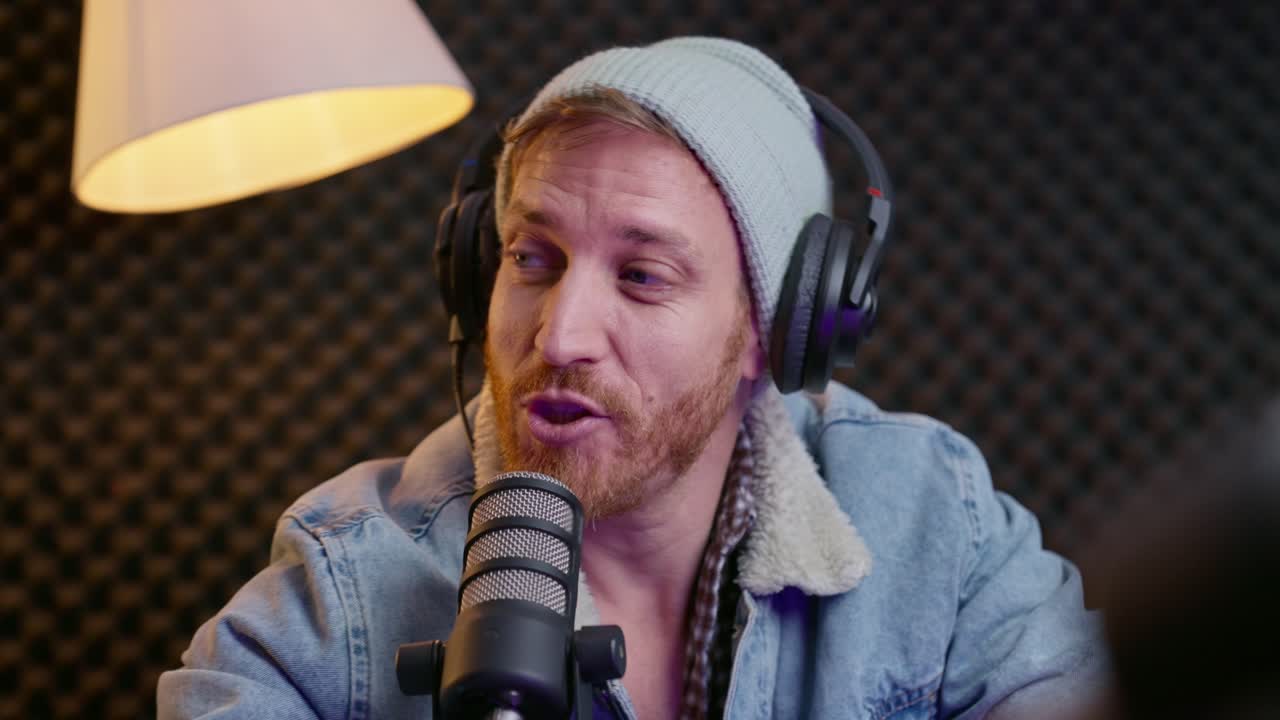 grabación de podcaster en un estudio profesional con auriculares y un micrófono. fondo de espuma acústica, iluminación cálida y ropa casual crean un ambiente moderno, creativo y acogedor