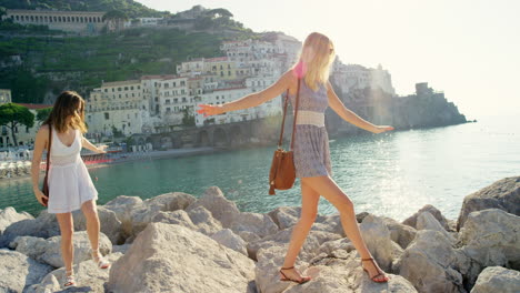 women, balancing and walking on beach rocks