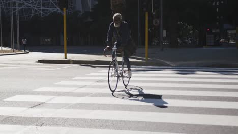 African-american-senior-man-riding-a-bicycle-crossing-the-road