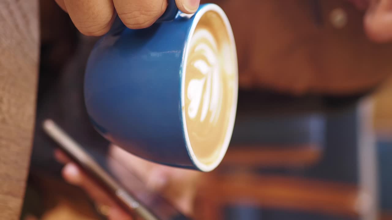 Person holding a cup of latte with foam art