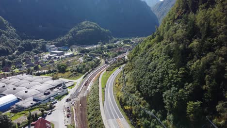 Straße-E16-Und-Eisenbahn-Von-Bergen-Vorbei-An-Der-Stadt-Dale-Mit-Dale-Of-Norway-Industriegebäude-Der-Firma-Unterhalb-Der-Straße-Links-Und-Eviny-Energy-Company-Im-Berghintergrund---Antenne