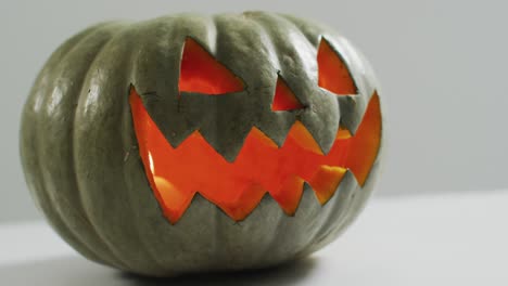 vista de cerca de la cara aterradora tallada calabaza de halloween contra un fondo gris