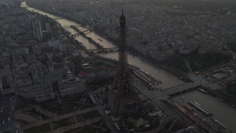 Orbit-shot-around-Eiffel-Tower.-Seine-River-calmly-flowing-through-urban-borough-in-background.-Paris,-France