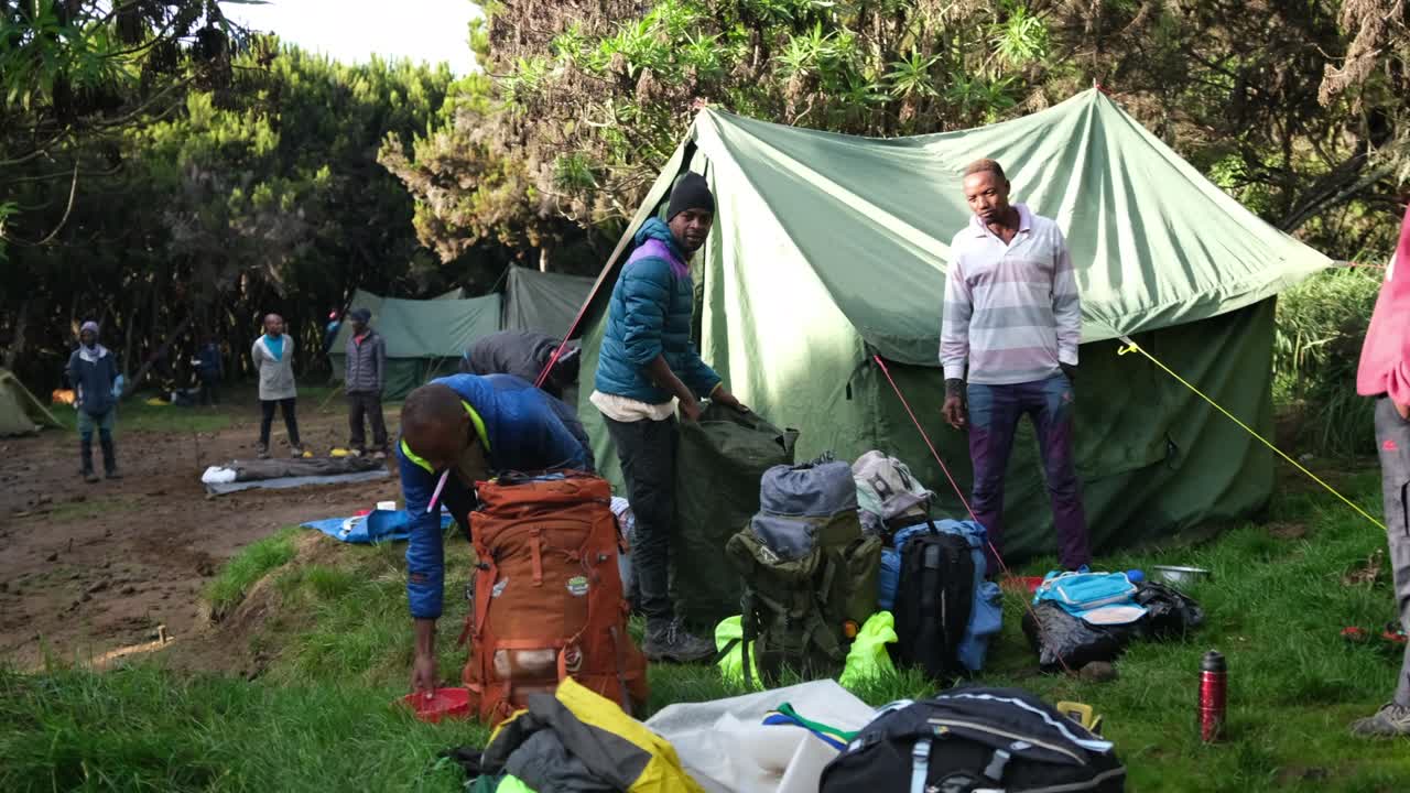 por la mañana en el campamento de machame el guía y el equipo reúnen el equipo y se preparan para escalar el kilimanjaro.