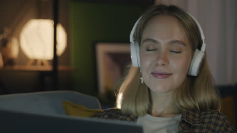 mujer relajándose en casa con auriculares y portátil