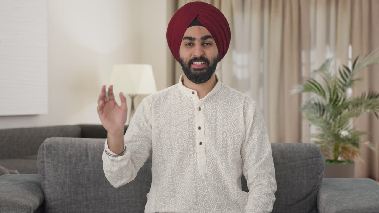 Uomo Sikh indiano felice che saluta con la mano