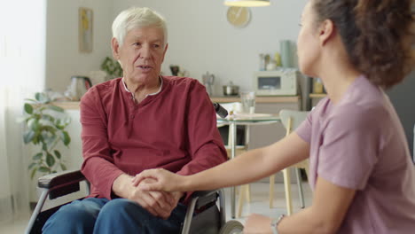 caregiver talking with senior man in wheelchair at home