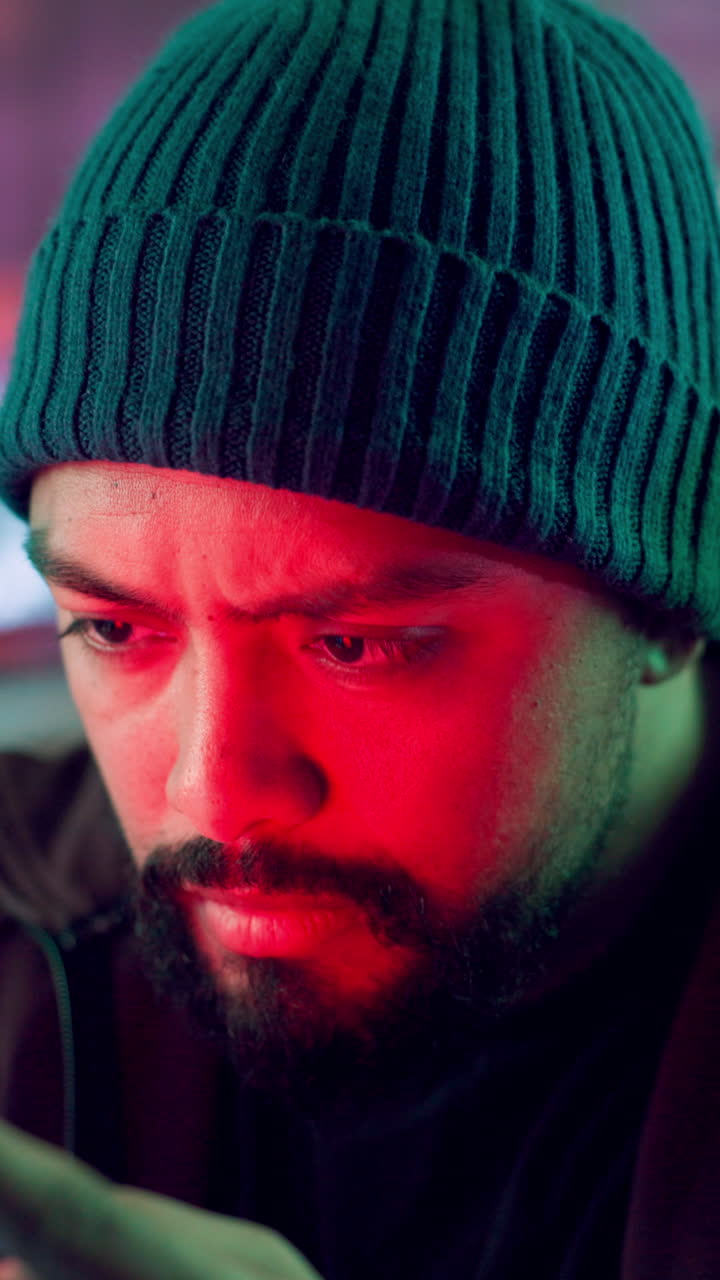 Focused Man in Beanie Using Smartphone with Changing Lights