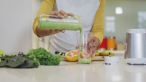 Mid-section-of-mixed-race-woman-preparing-healthy-drink-in-kitchen