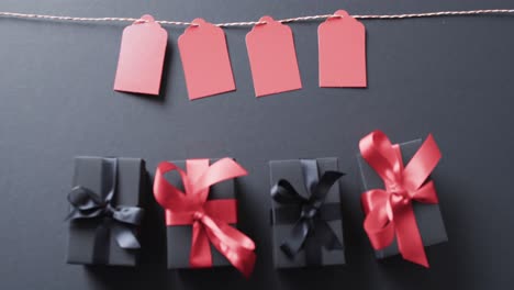 video of gift tags on string, gift boxes with ribbons and copy space on black background