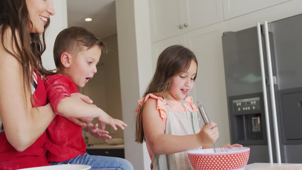Felice madre, figlia e figlio caucasici che cucinano insieme in cucina.